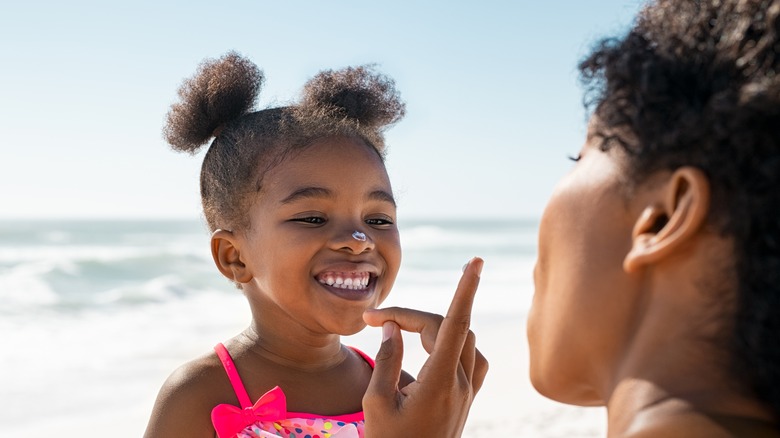 Woman applying sunscreen to girl