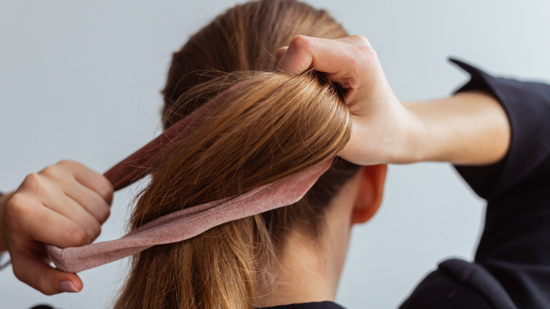 Woman tying hair in ponytail