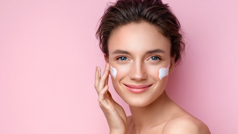 Woman applying moisturizer to face