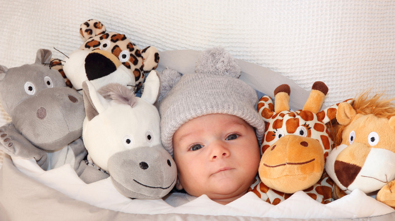 baby laying with stuffed animals