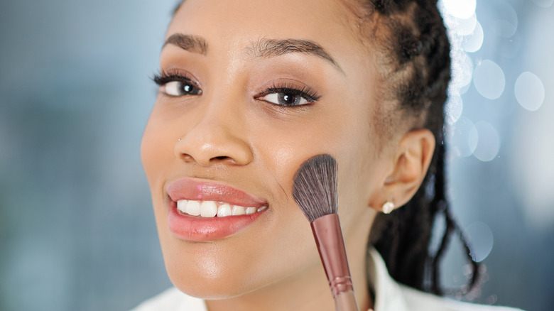 Woman putting on peach blush