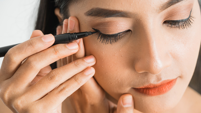 Woman applying liquid eyeliner