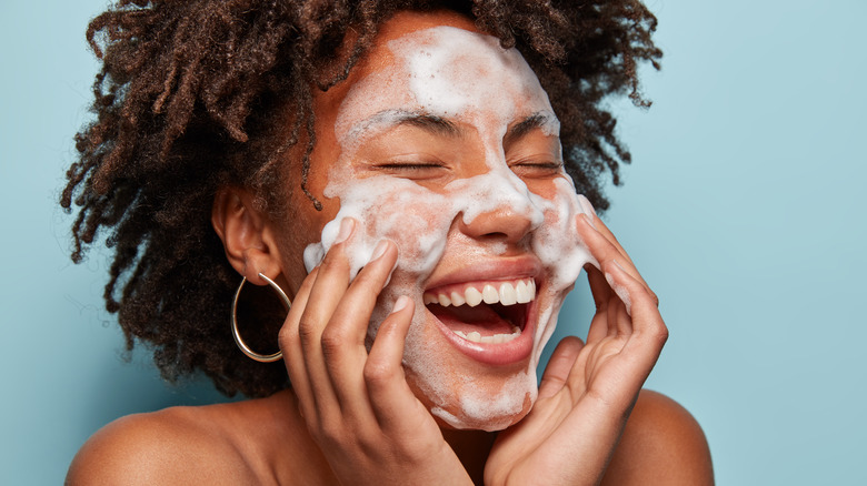 Woman smiles while using foaming cleanser