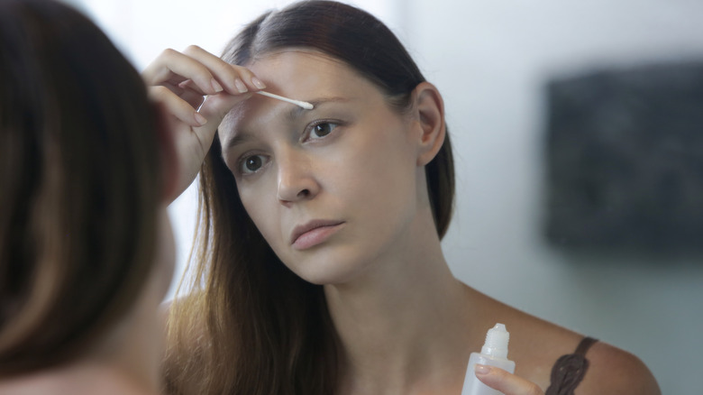 Woman applying an eyebrow growth serum