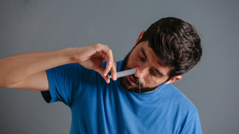 Man flushing his nose with syringe and saline