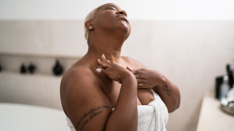 Woman moisturizing her chest