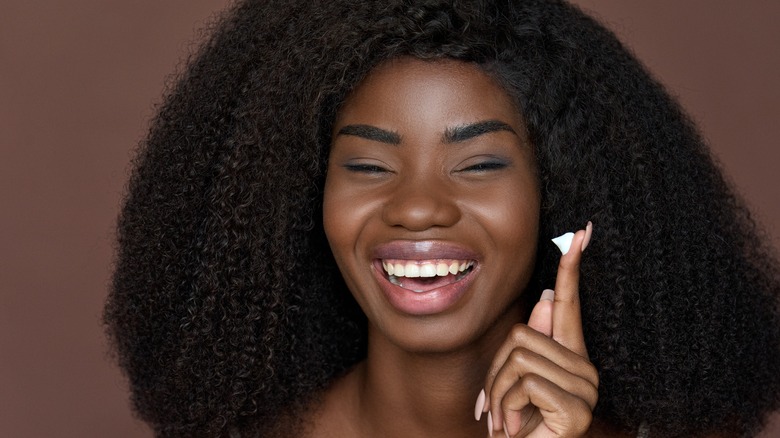 Woman smiling with lotion on finger