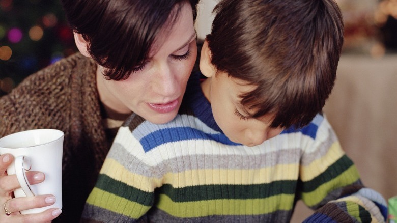 woman helping boy with writing