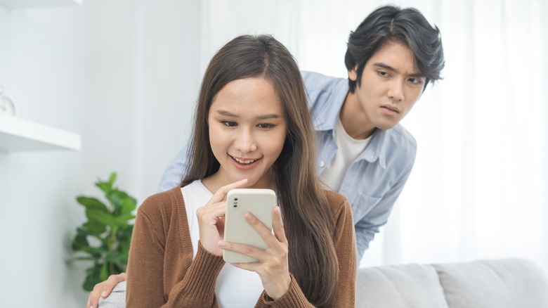 Man peering over girlfriend's shoulder