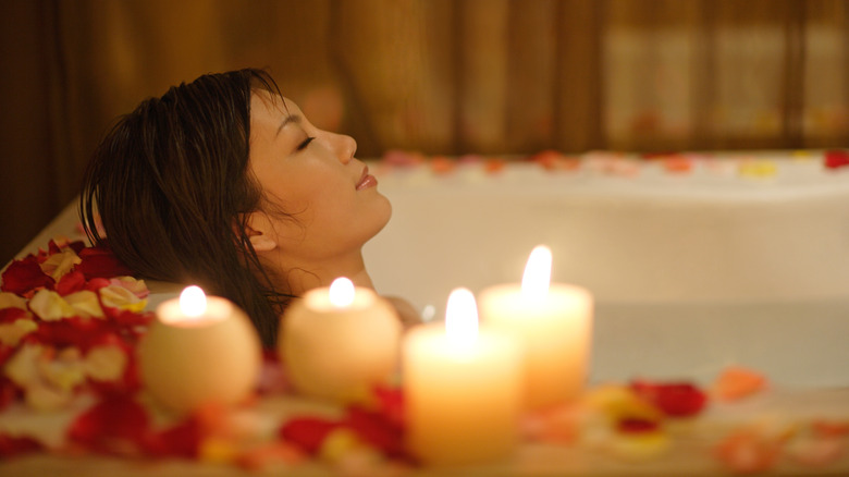 Woman takes a bath with candles