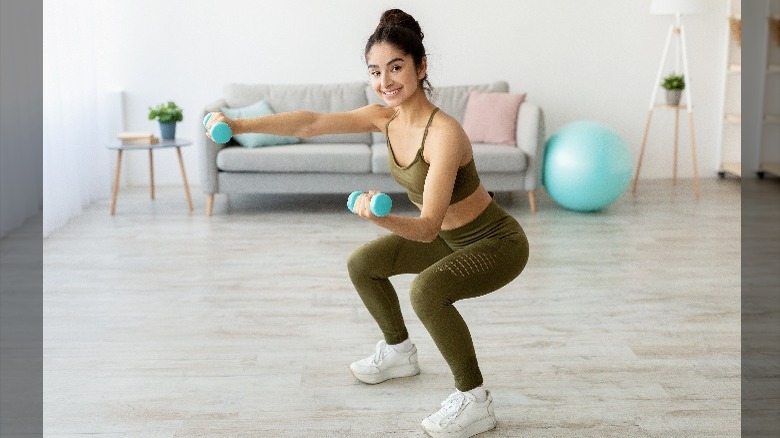 A woman squatting with weights 