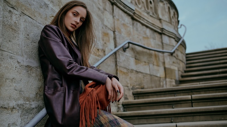 Stylish woman leaning against wall