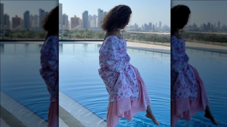 woman in pink outfit dipping her toes in water