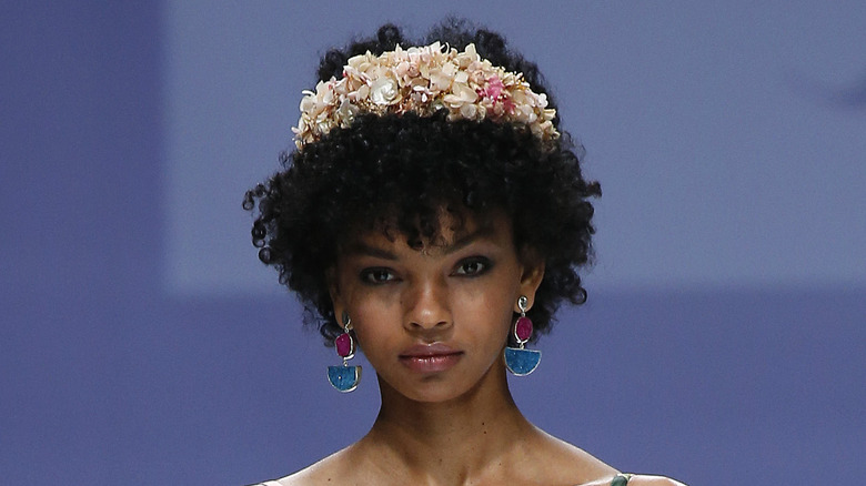 A woman with curly hair wearing a flower crown