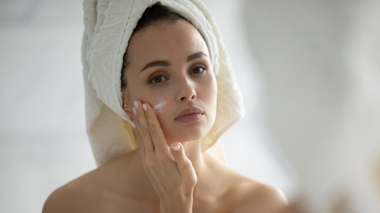A woman applying skincare product on her cheek