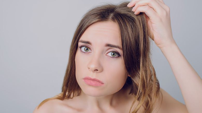 Photo of a nervous girl examining her hair