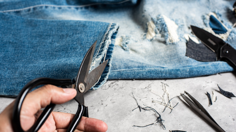 person cutting hems of jeans