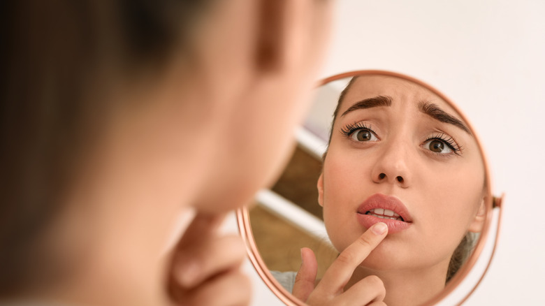 A concerned woman touching her lips in a mirror 