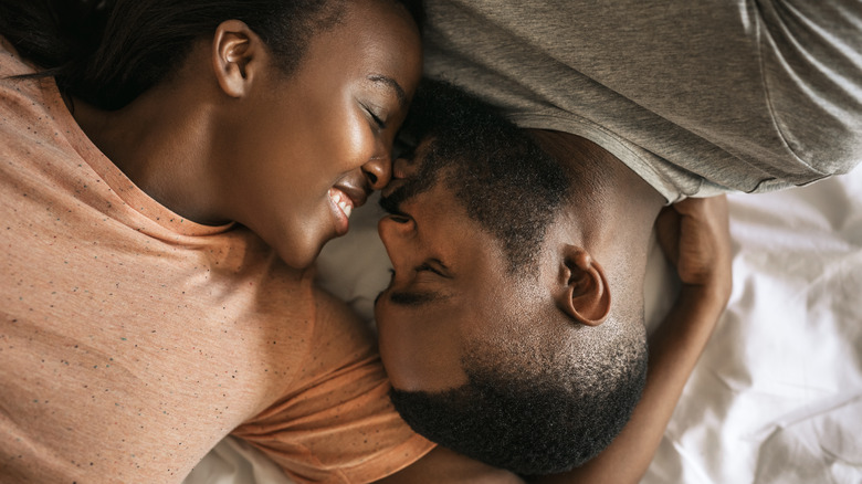 Happy man kissing woman's nose in bed