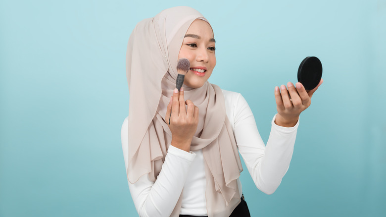 woman putting on bronzer 