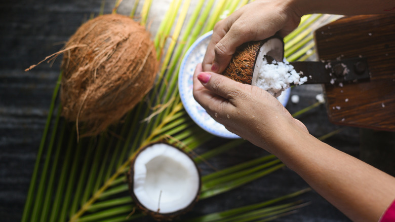 Woman grating coconut into bowl