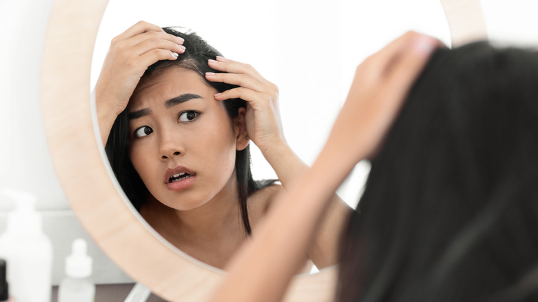 Worried woman examining hair