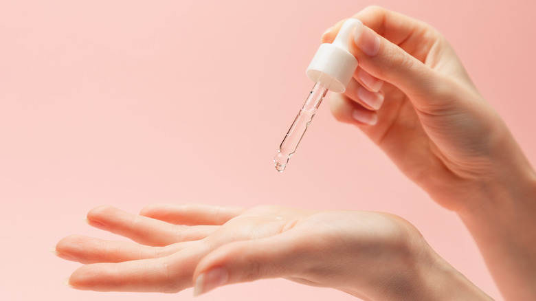 Woman dropping serum in hand