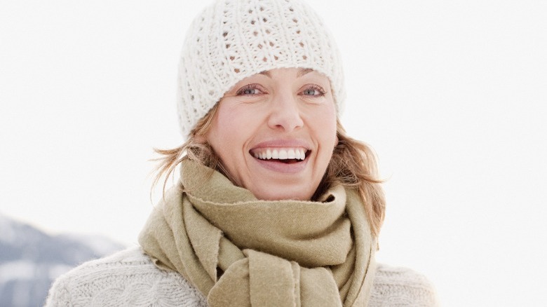 Woman smiling wearing a white beanie and beige scarf in winter