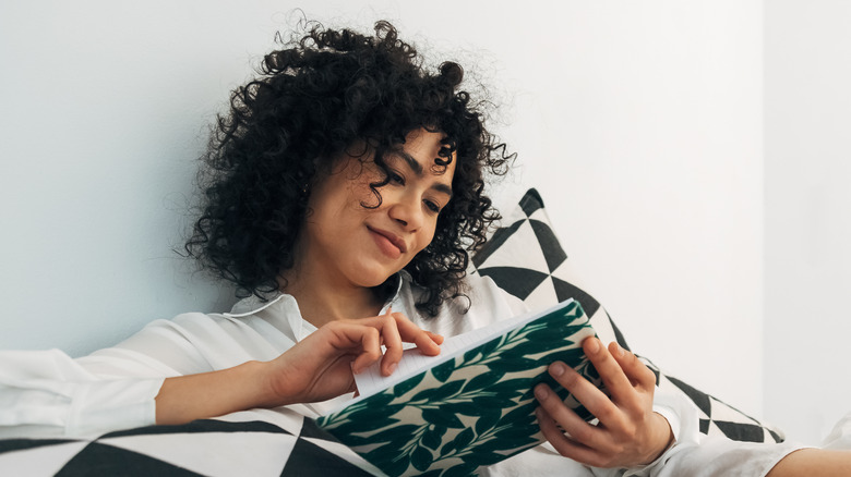 smiling woman in bed journaling