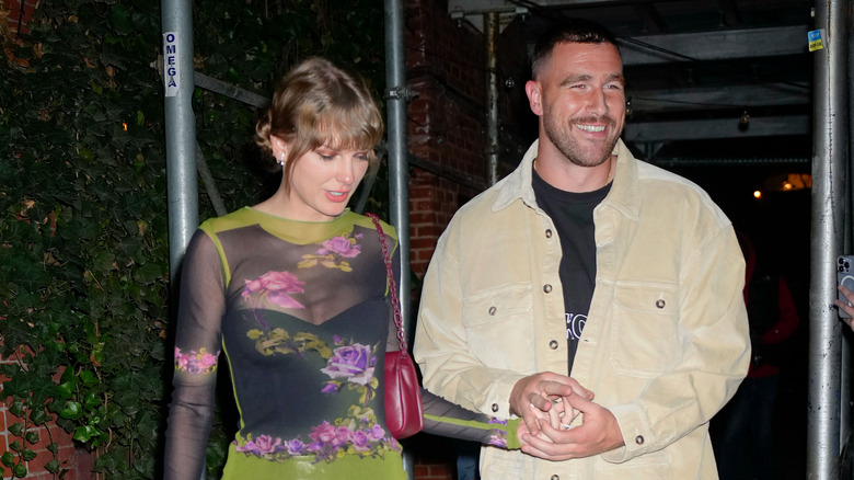 Taylor Swift and Travis Kelce walking out of a restaurant