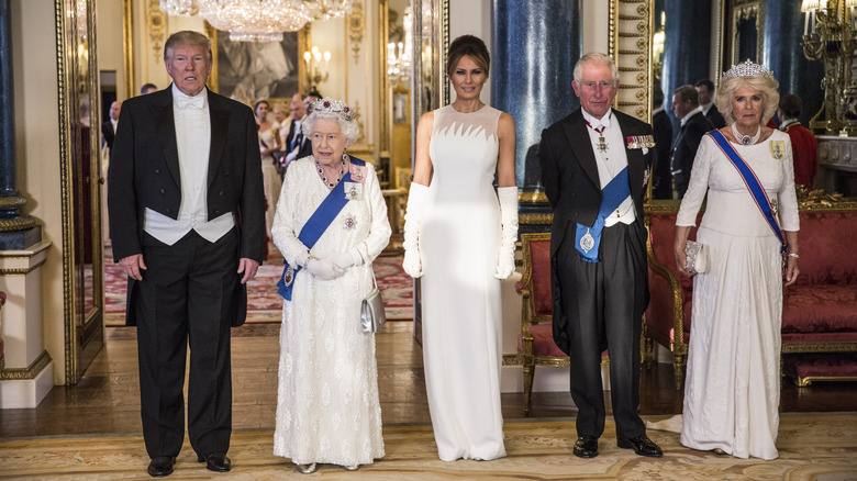 Donald Trump, Queen Elizabeth, Melania Trump, King Charles, and Queen Camilla standing inside