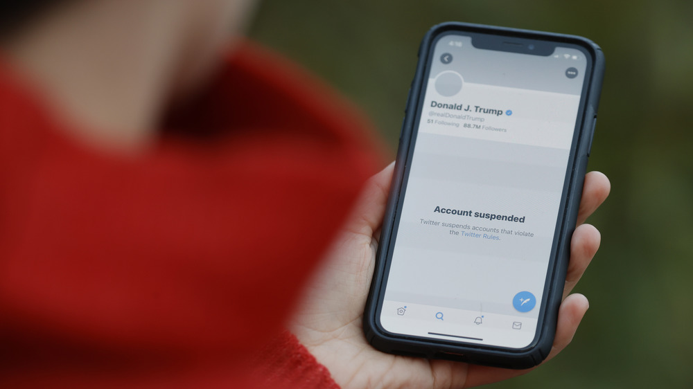 Woman looking at phone showing Trump is suspended