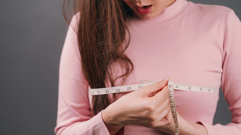 woman measuring bra size over shirt