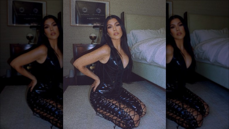 Kourtney Kardashian posing in a leather, tie-up jumpsuit