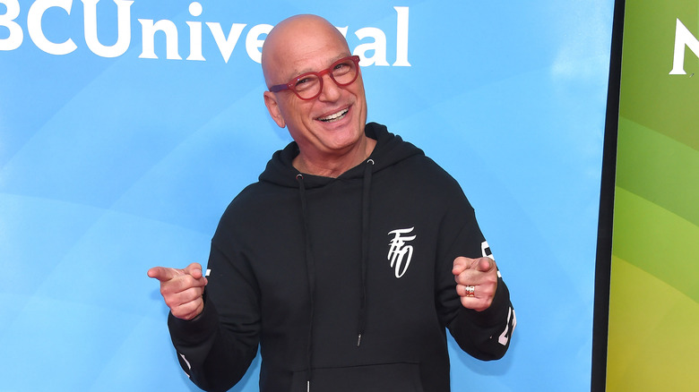 Howie Mandel points his fingers in a black hoodie.