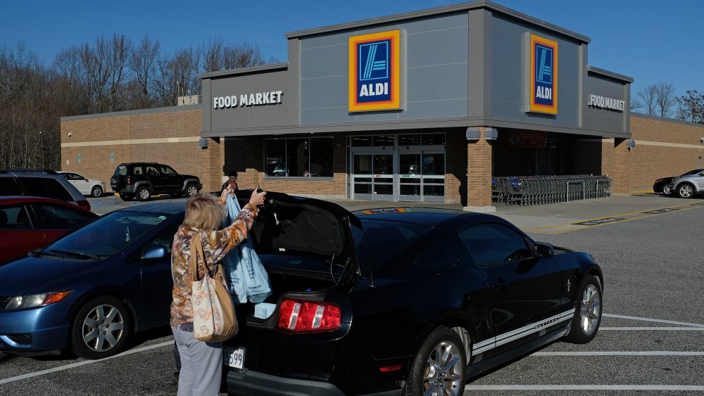 A woman loading groceries in her car outside Aldi