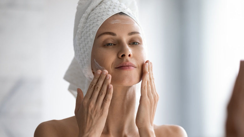 A woman applying face cream 