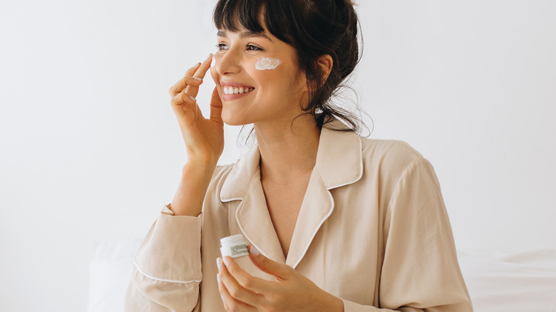 A woman applying face cream 