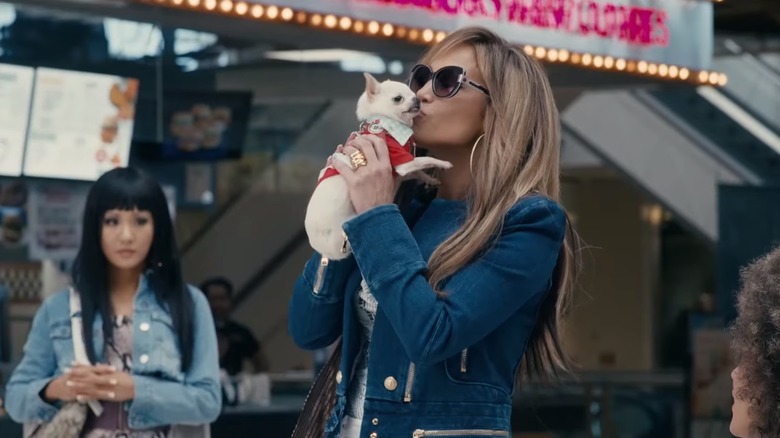 J-Lo kissing a dog as Constance Wu looks on in Hustlers