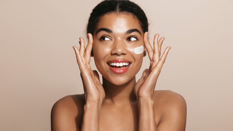 Woman applying moisturizer to face