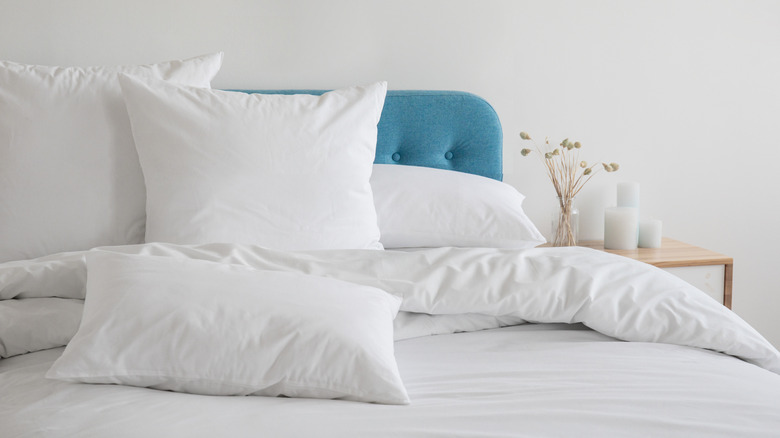 white pillows on a white bed with a blue headboard