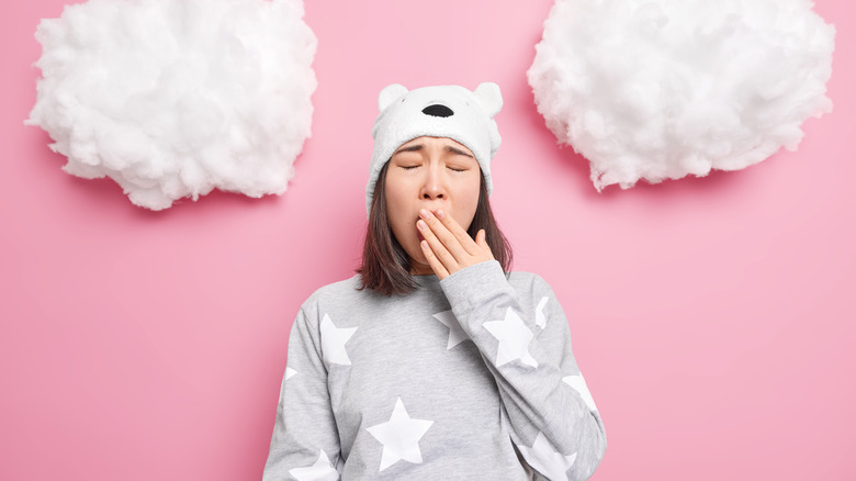 Woman yawning with clouds behind her