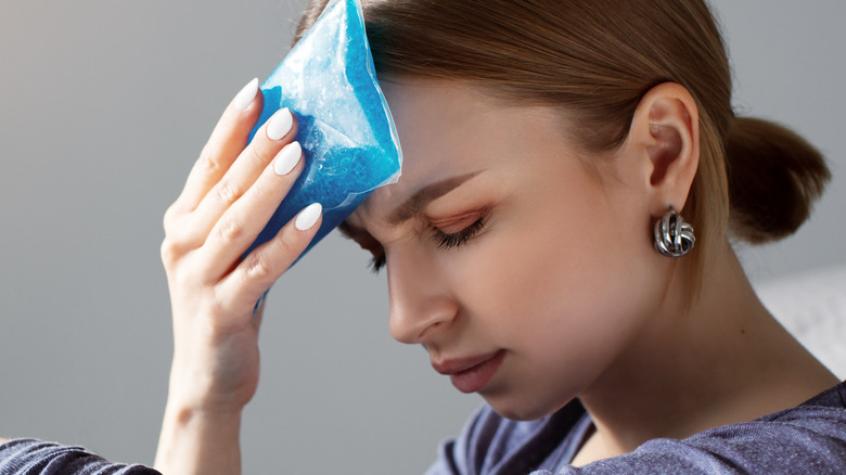 Woman applying cold pack to her head 