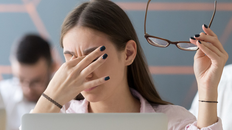 Young woman experiencing a migraine at work