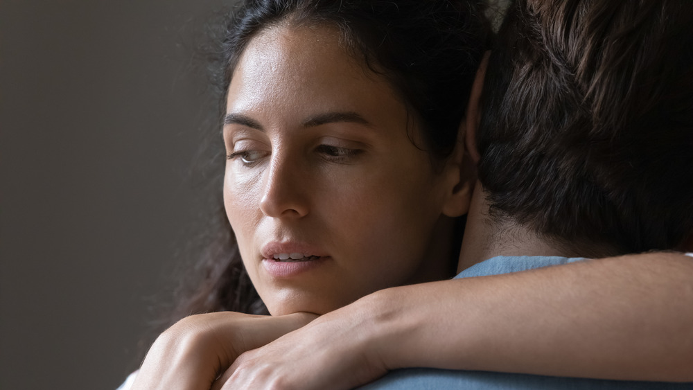 Woman looking thoughtful while hugging a man