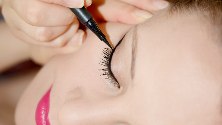 Woman applying liquid eyeliner 