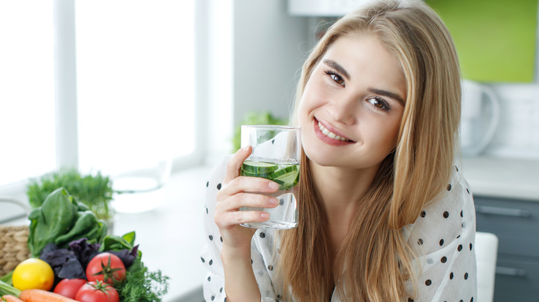 Woman drinking water infused with cucumbers