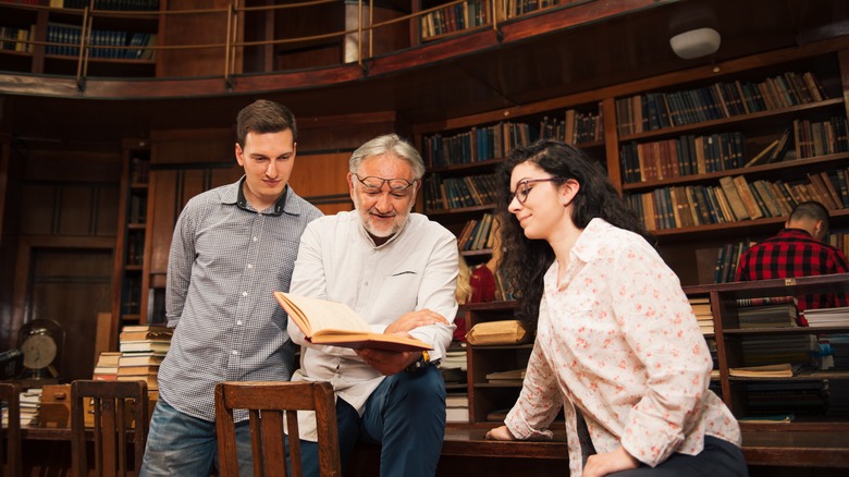 Group of people reading a book in a library