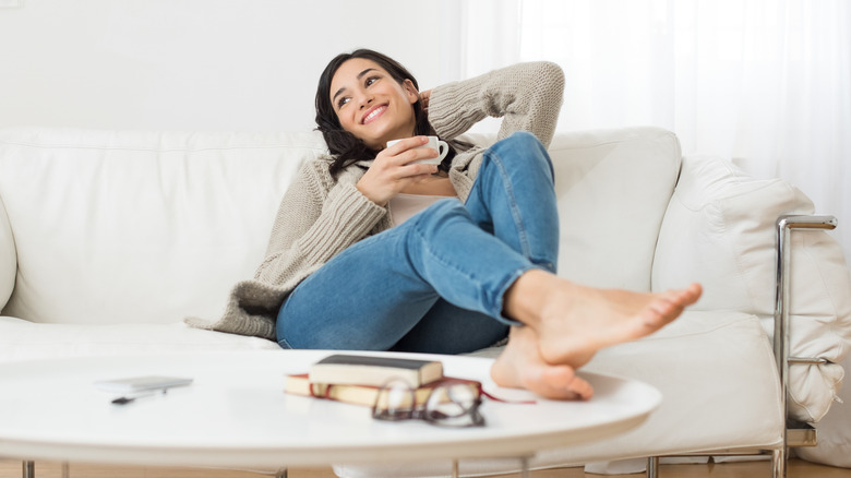 Young woman smiling while sitting on the sofa with her feet up on the table