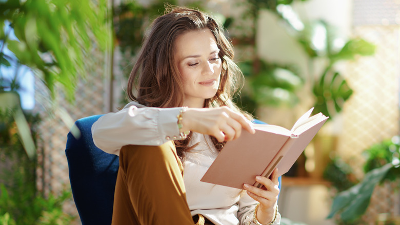 Young woman smiling while reading a book